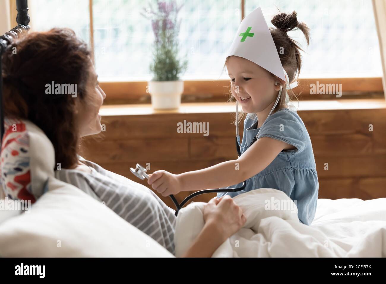 Daughter holds stethoscope imagines herself doctor listen mother heartbeat Stock Photo