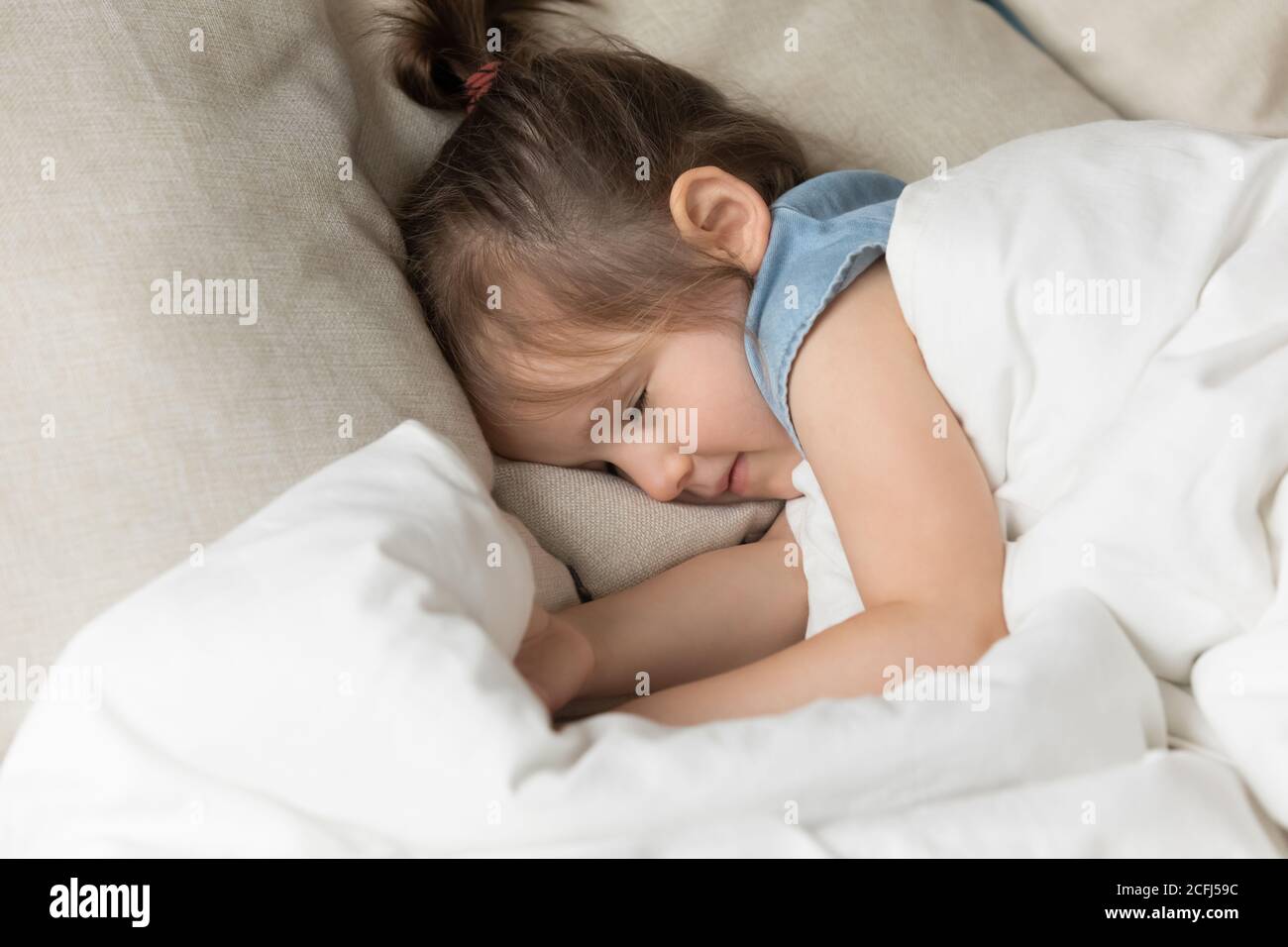 Little girl sleeping in bed under warm duvet closeup view Stock Photo