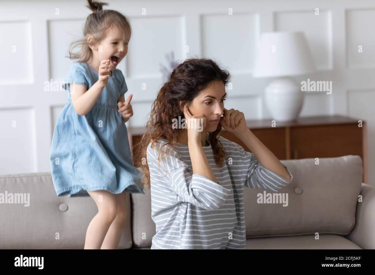 Mother cover ears with fingers not listen uproar of daughter Stock Photo