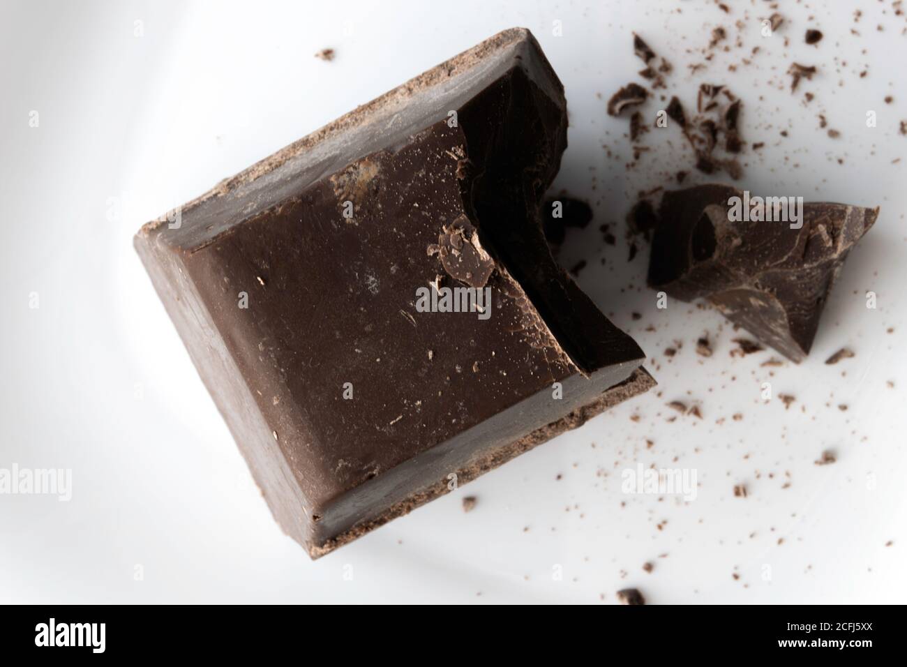 a large chopped piece of chocolate lies on a white ceramic plate Stock Photo