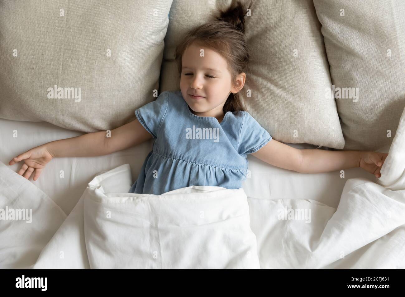 Top view little girl enjoy healthy day nap lying on bed Stock Photo