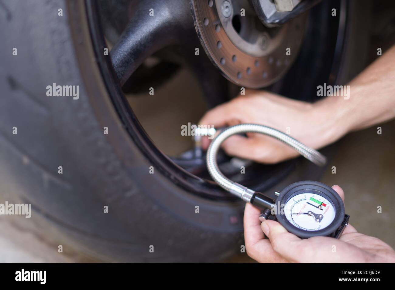Man checking manually air pressure of motorcycle wheel before traveling Stock Photo