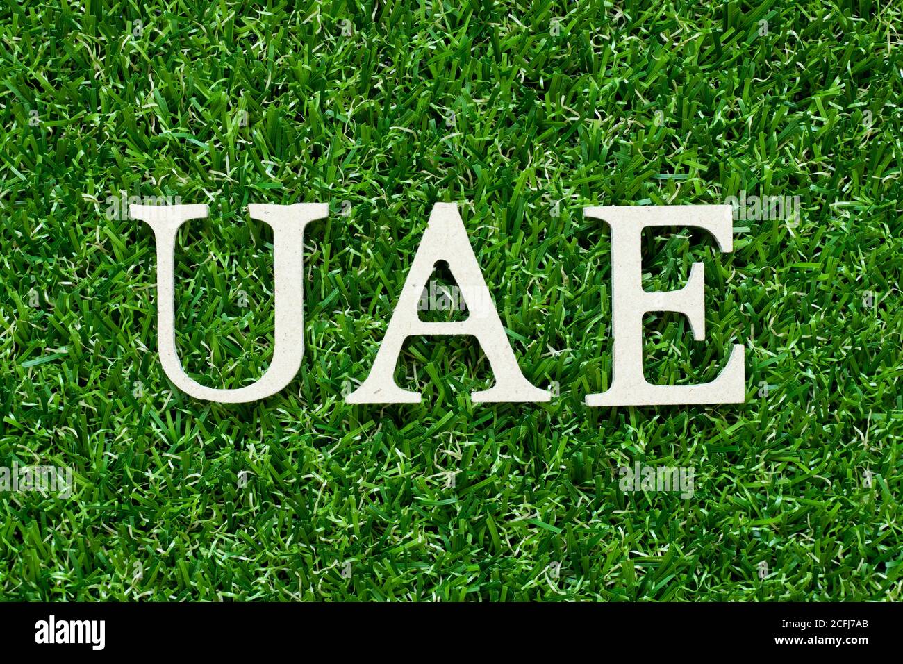 Wood alphabet letter in word UAE (Abbreviation of United Arab Emirates) on green grass