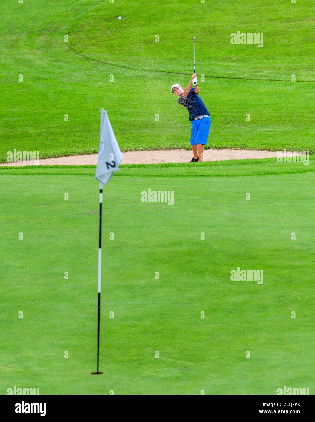 Teenager on a golf course in the Allgäu, playing golf in a beautiful landscape. Stock Photo