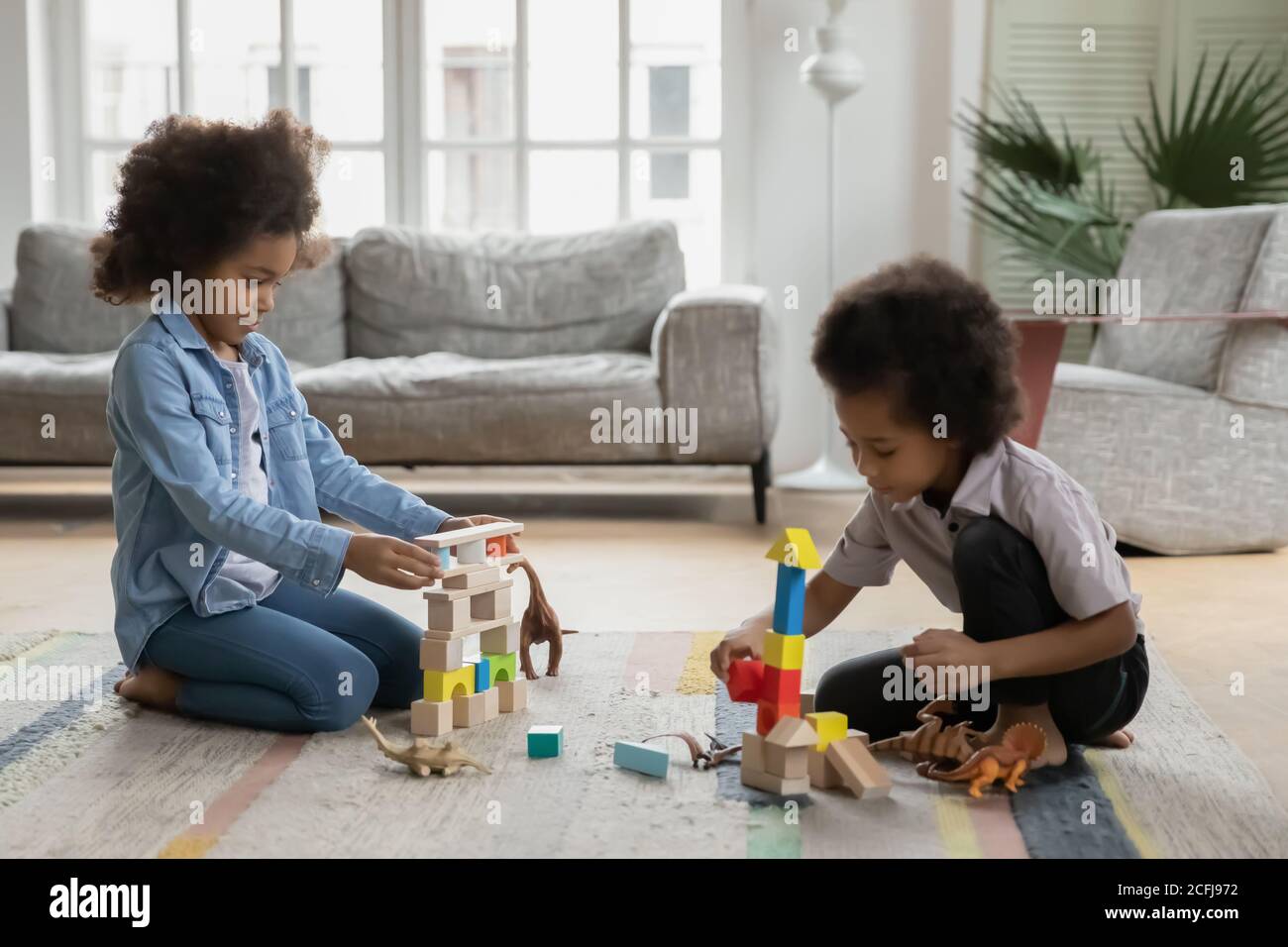 Smiling adorable mixed race small children siblings playing toys. Stock Photo