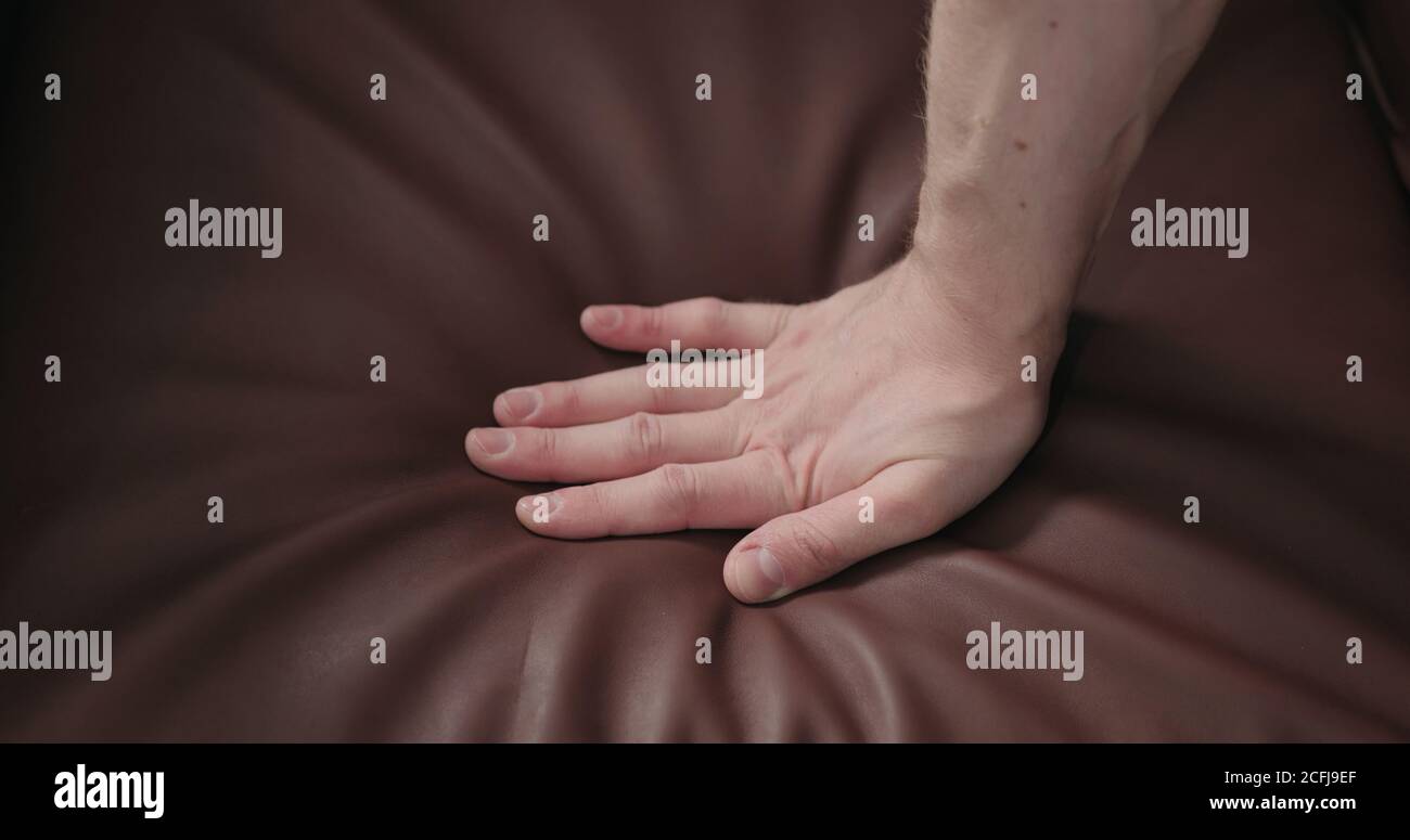 man hand checking brown leather cushion closeup, wide photo Stock Photo