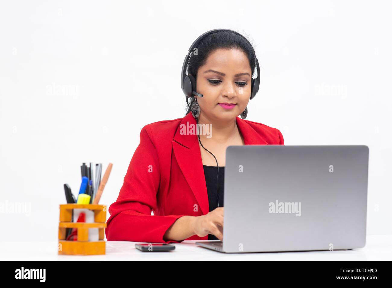Portrait of professional Indian businesswoman wearing headphones and working from her computer, Freelancer, work from home, Corporate lady. Stock Photo