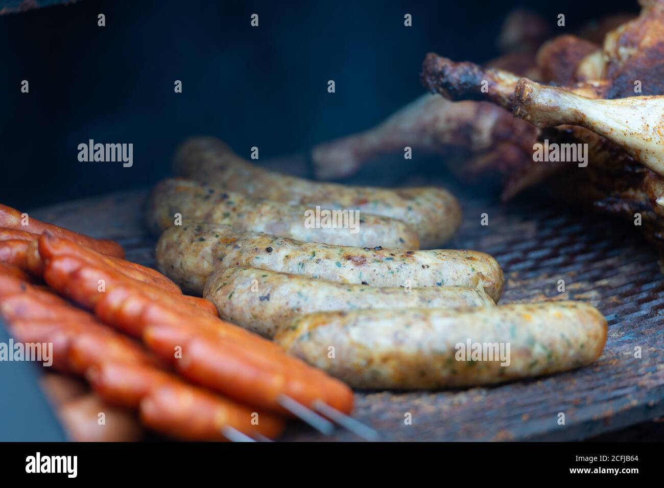 Fresh sausage and hot dogs grilling outdoors on a gas barbecue grill. Stock Photo