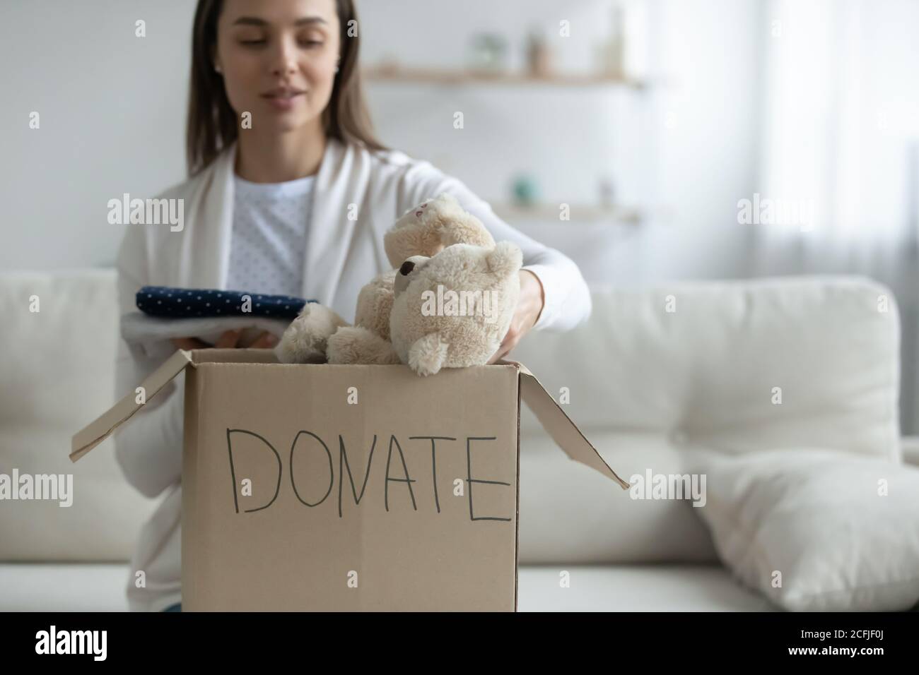 Kind young woman donating things to homeless people. Stock Photo