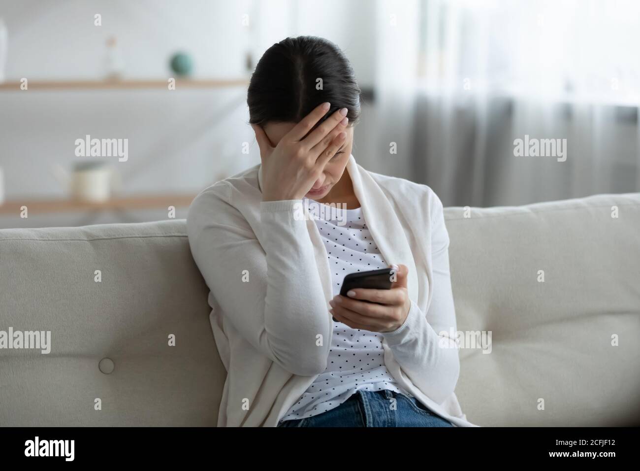 Stressed young woman feeling confused of bad news notification. Stock Photo