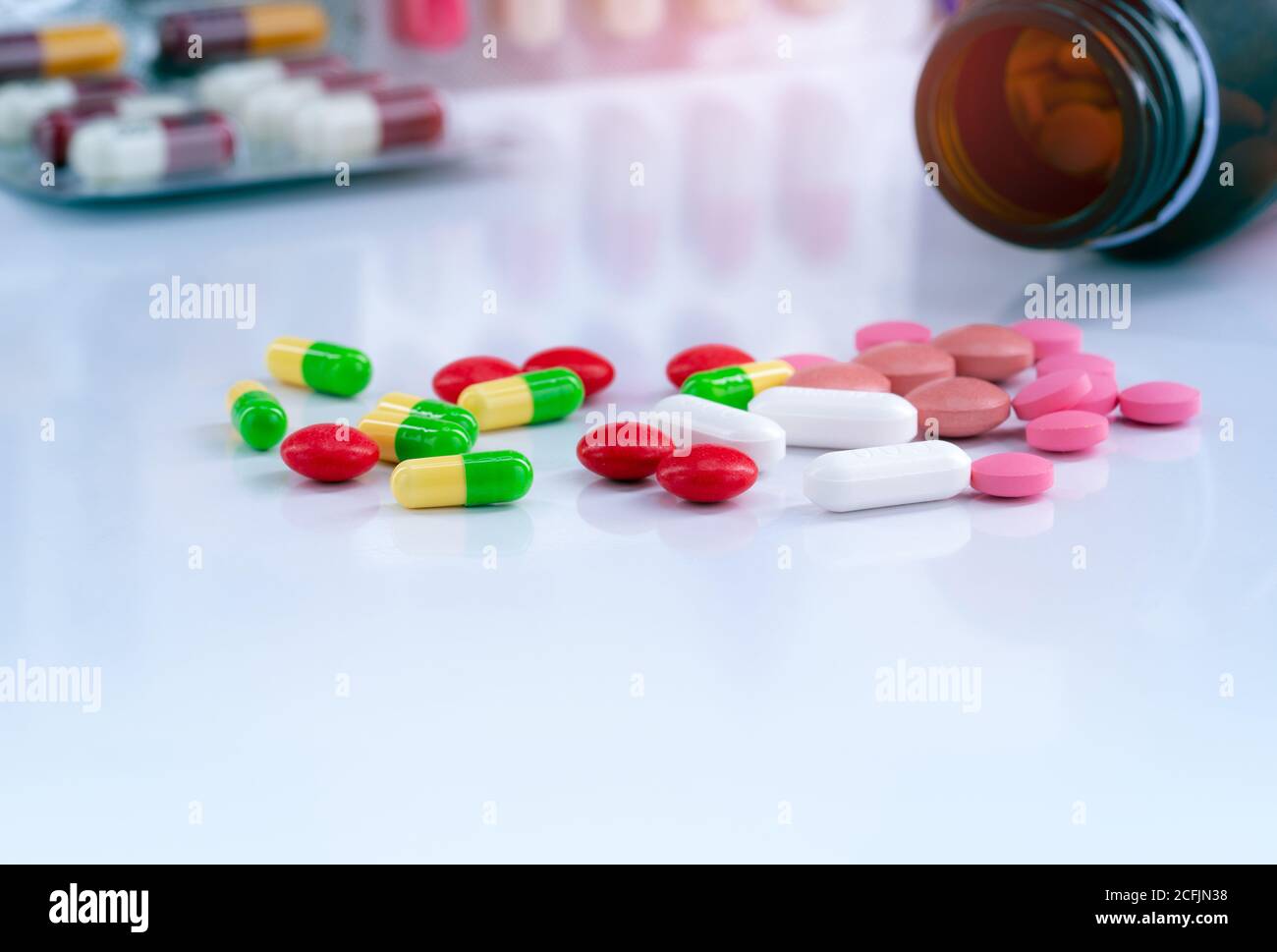 Colorful tablets and capsule pills on blurred background of drug bottle and antibiotic capsule pills. Pharmaceutical industry. Background for content Stock Photo