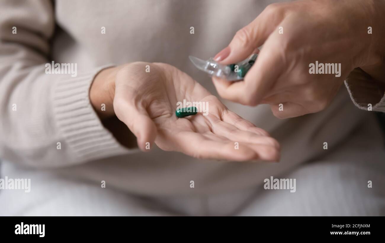 Close up mature woman taking pill out of packaging Stock Photo