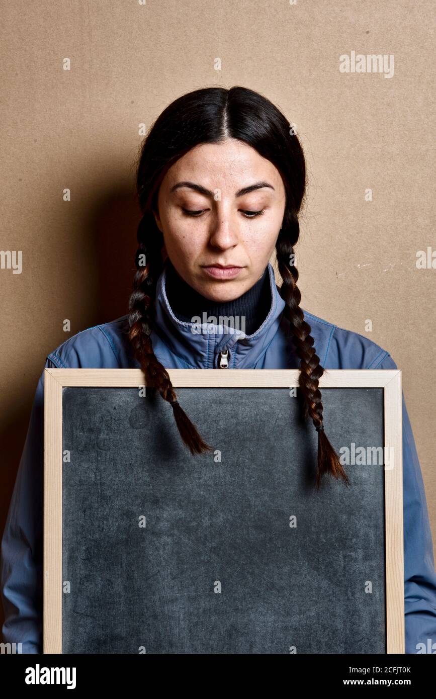 girl with no make up and pigtails looking down and hold chalkboard Stock Photo