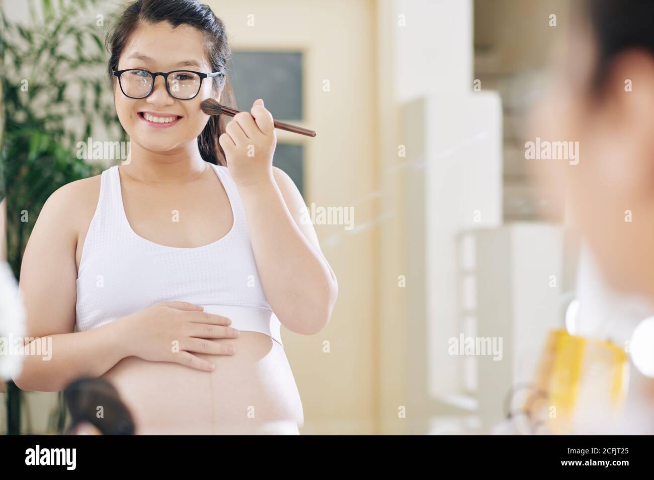 Pregnant woman applying make-up Stock Photo