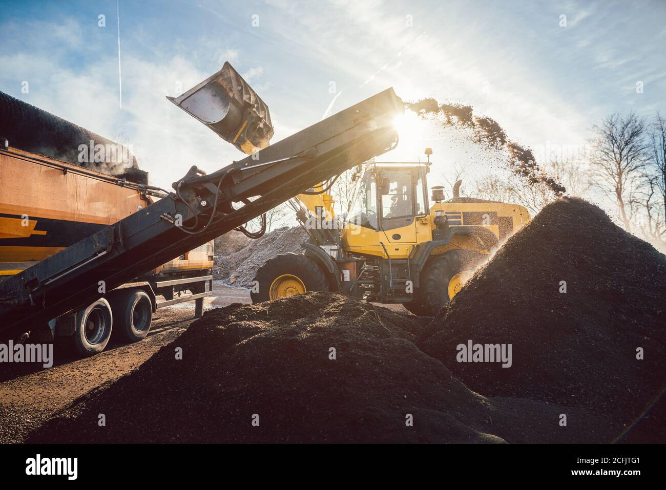 Heavy machinery moving earth and biomass in compost works Stock Photo