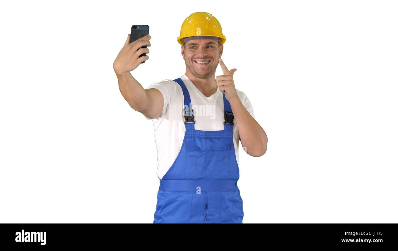 Smiling handsome young builder making selfie with mobile phone on white background. Stock Photo