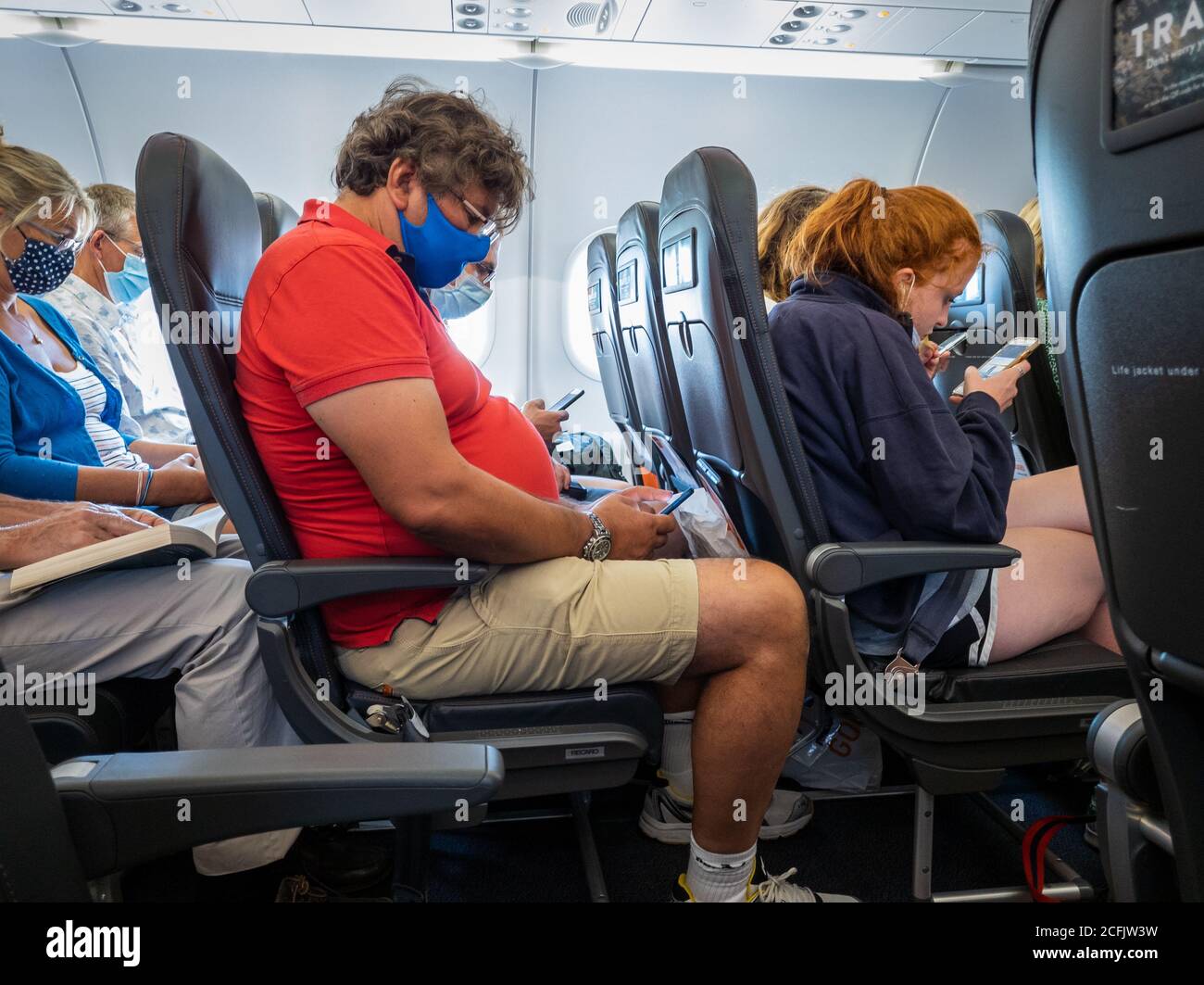 Passengers wearing face mask/ covering onboard a EasyJet flight. Stock Photo