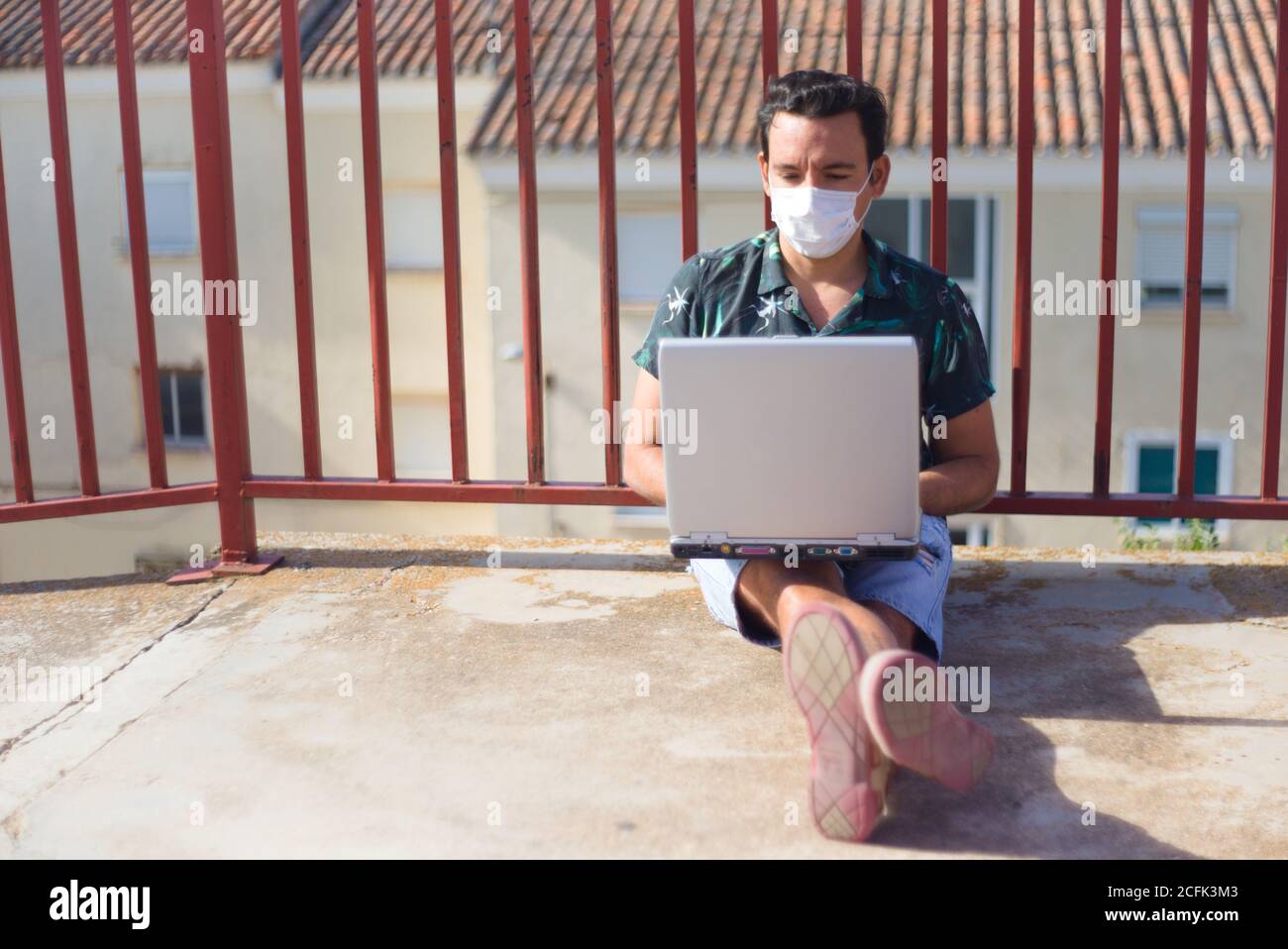 Man teleworking online outdoors with a laptop computer and covid mask. Stock Photo