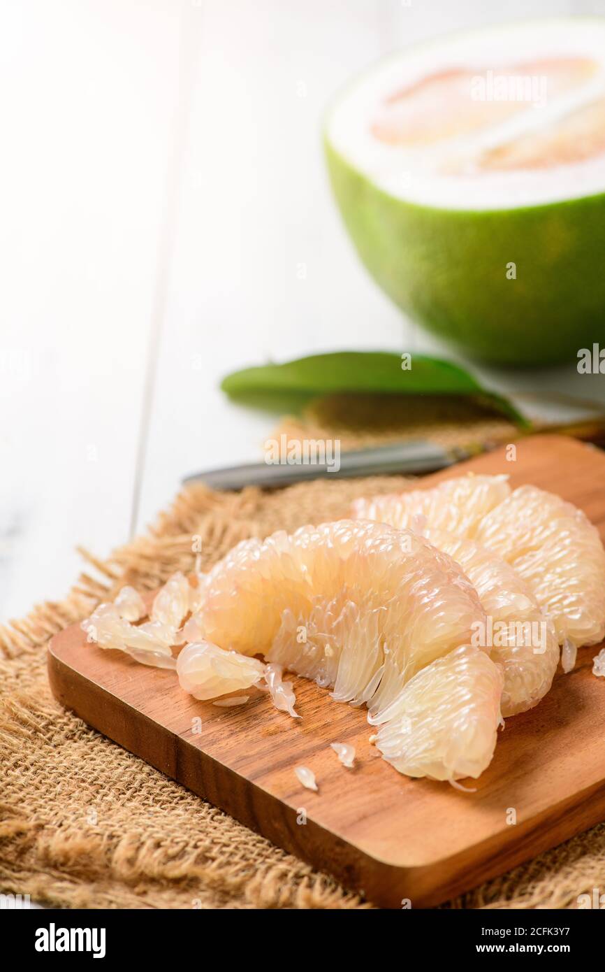fresh peeled Pomelo or grapefruit on wood plate. Seasonal fruit of