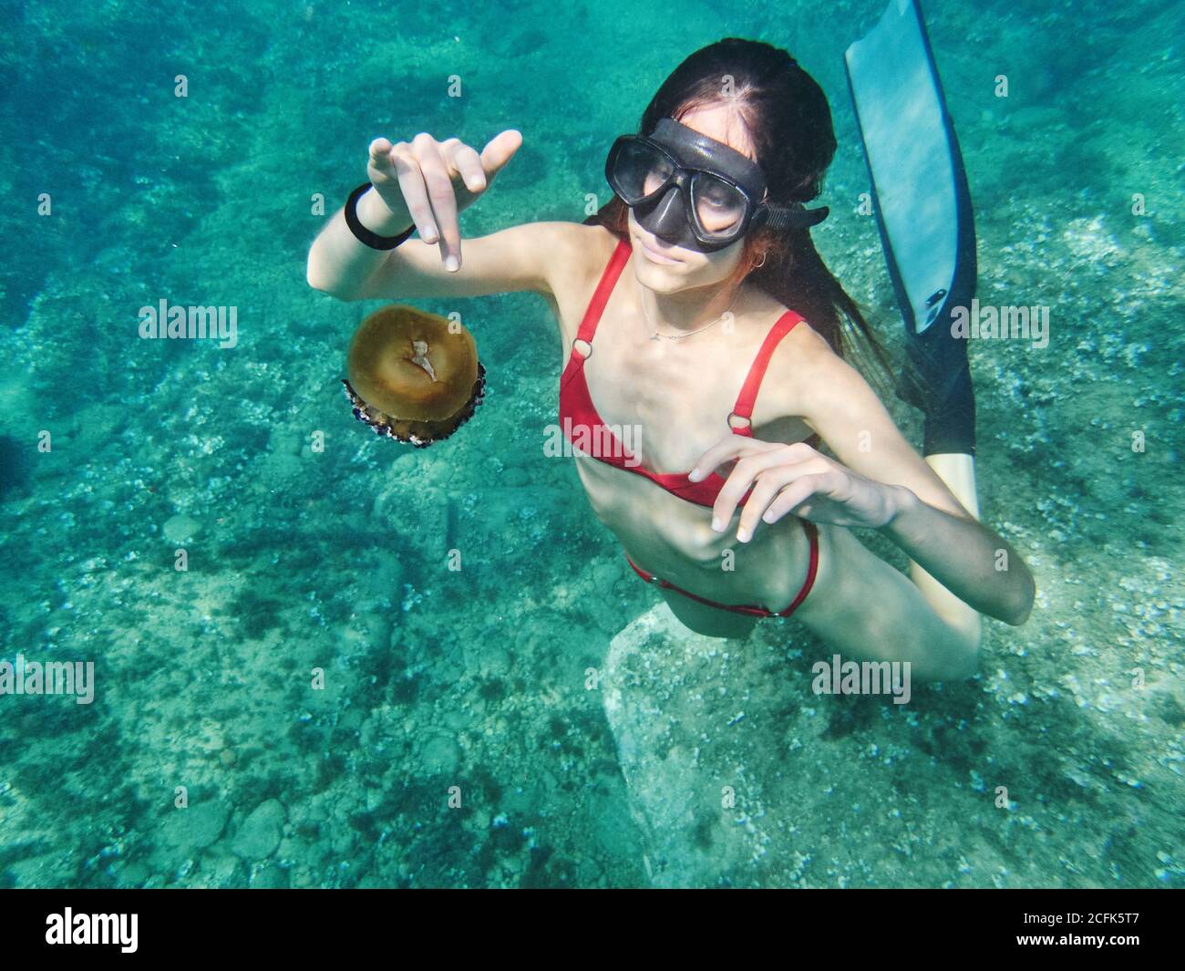 unrecognizable young Woman in diving mask swimming in deep transparent