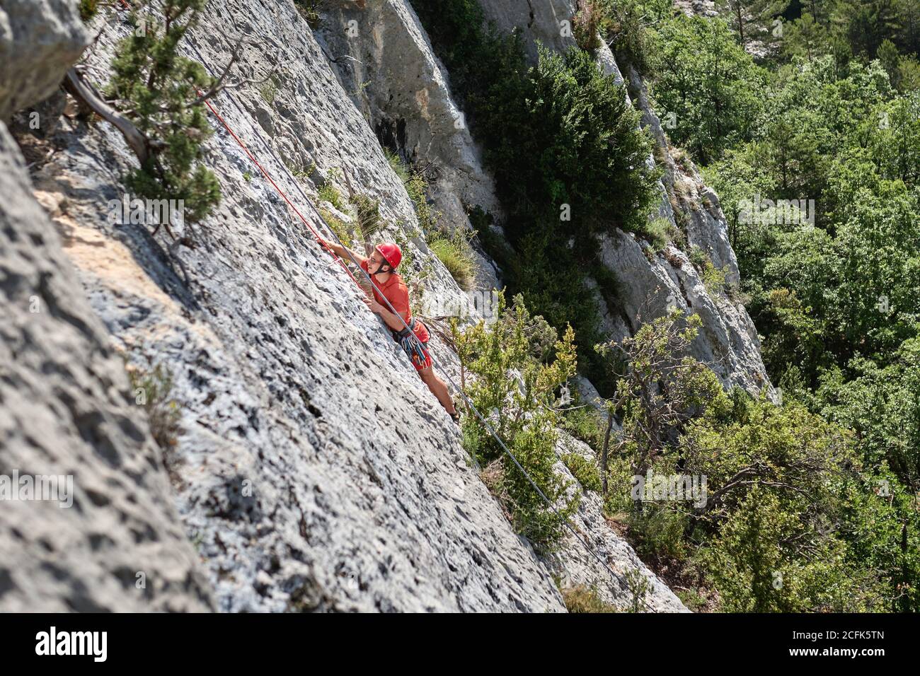 Side view of mountaineer in safety equipment climbing steep rock during