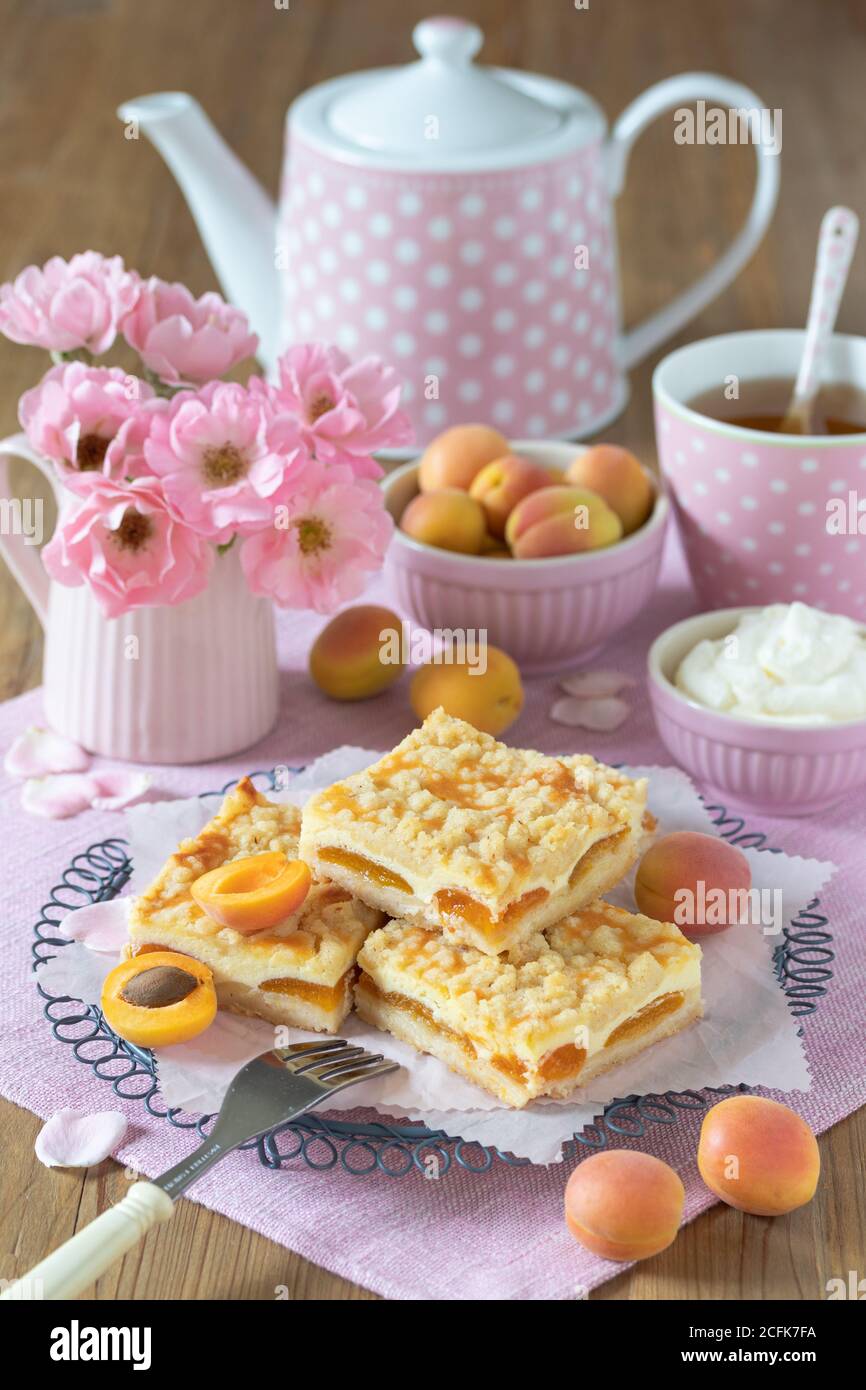 table decoration with apricot cake with crumble, tea dishes and bouquet of roses Stock Photo