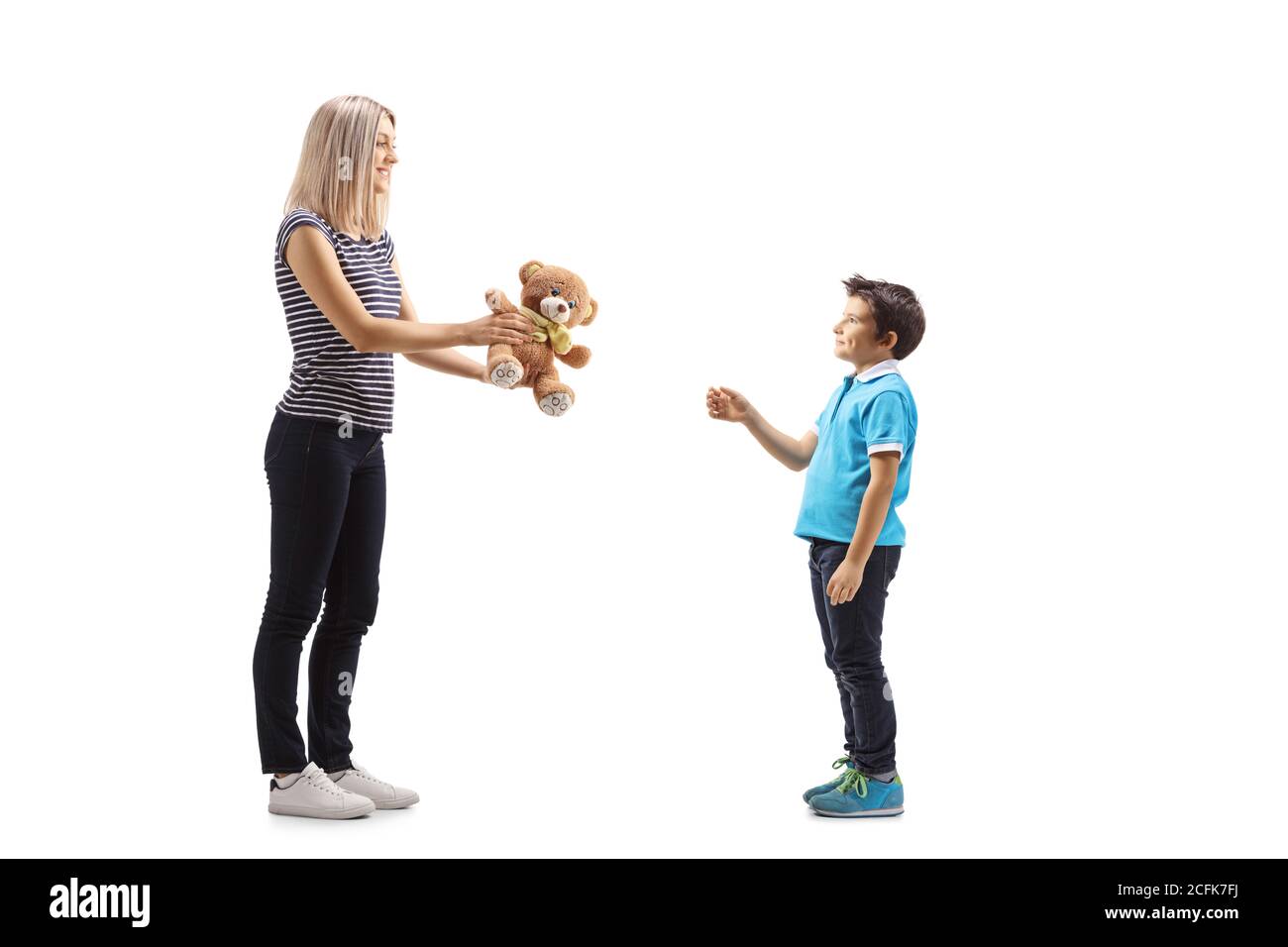 Full length profile shot of a woman giving a teddy bear to a boy isolated on white background Stock Photo