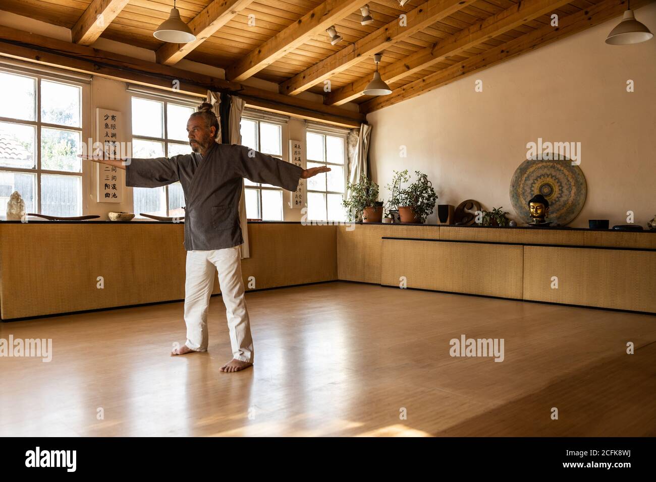 Full body senior ethnic male doing traditional chi kung movements ...