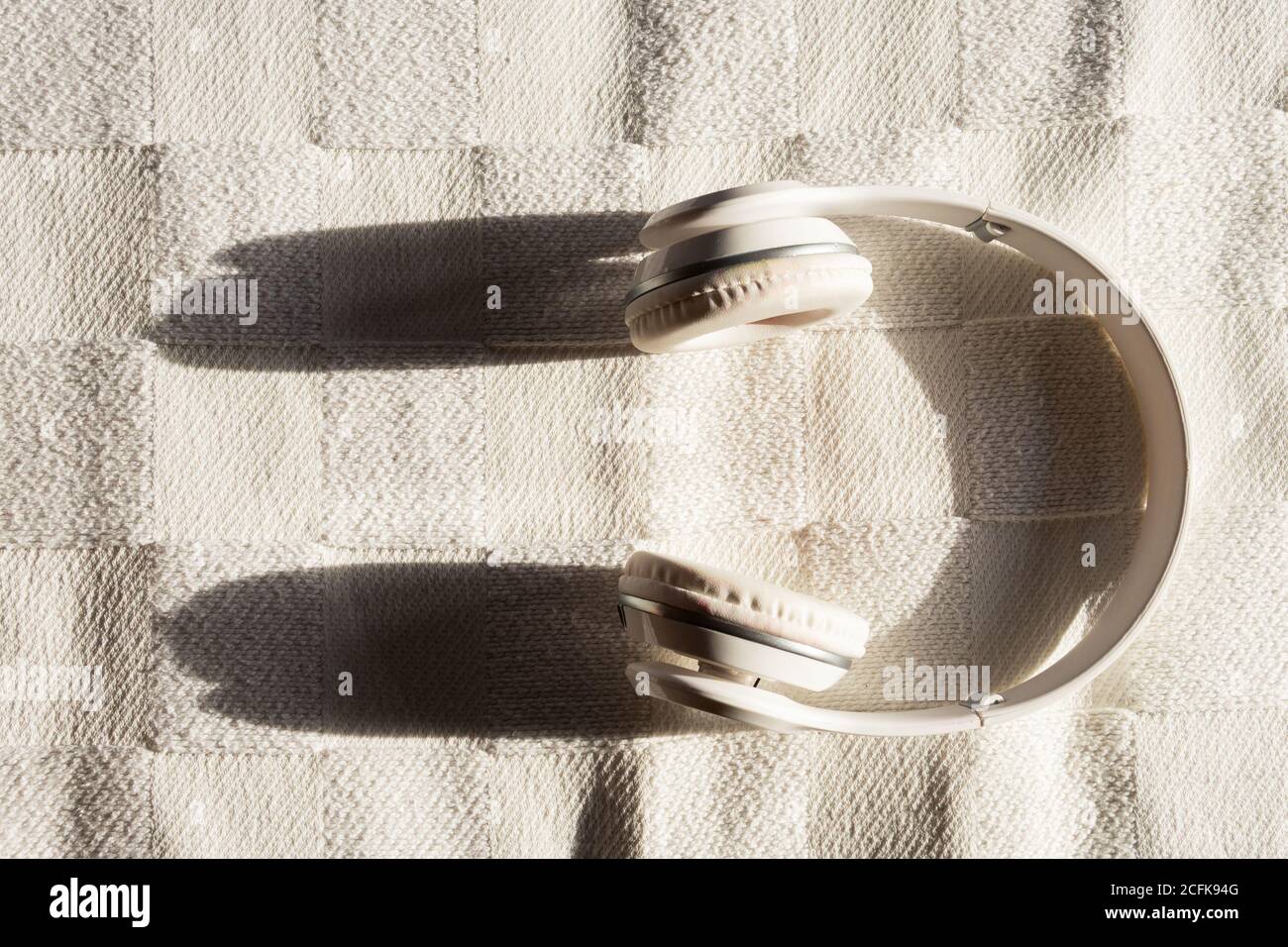Top view of contemporary headset placed on white checkered coverlet on sunny day Stock Photo