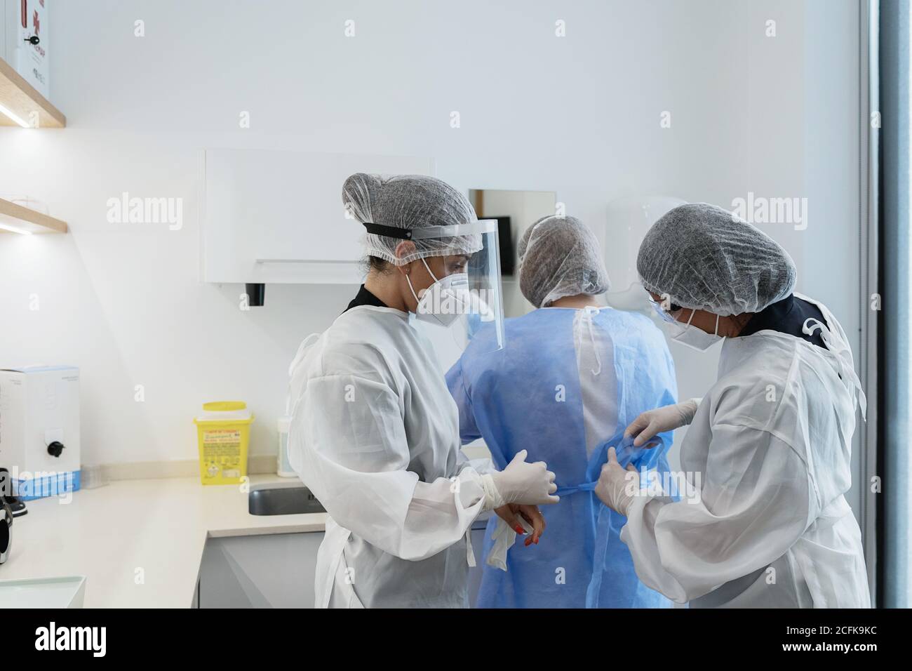 Female medical workers in protective masks and face shields helping