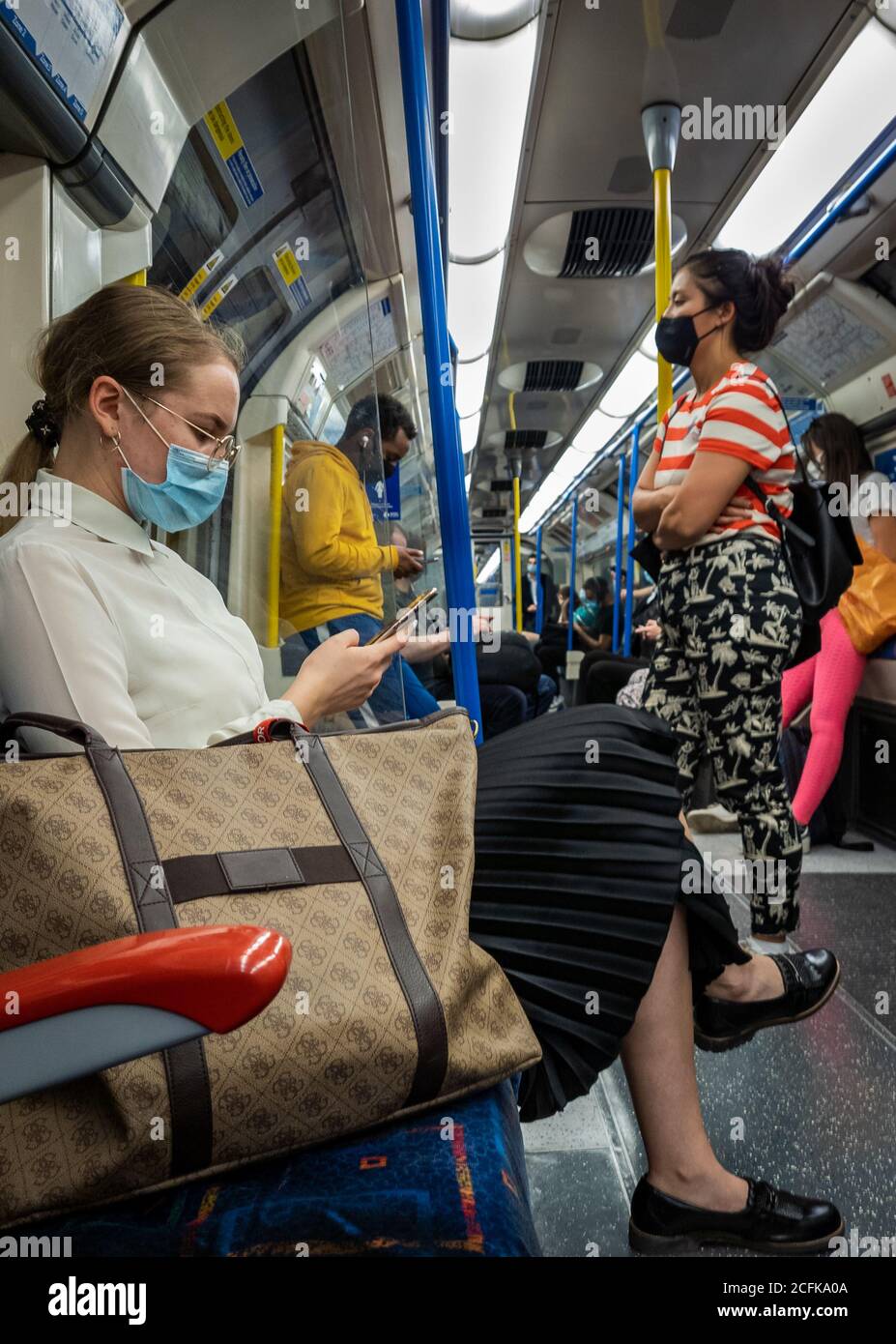 Passengers on the London Underground train carriage wearing face covering and trying to practice social distancing. Stock Photo