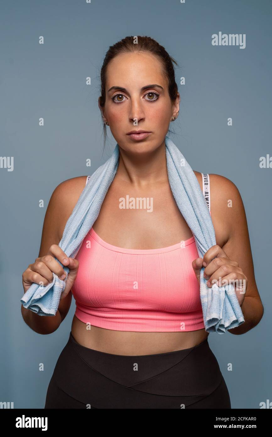 Portrait of a active and curvy young caucasian woman posing with a towel on her shoulders isolated on a blue background. Stock Photo