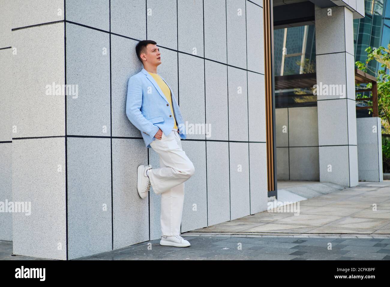 Young man on the street leaning on wall and looking away Stock Photo