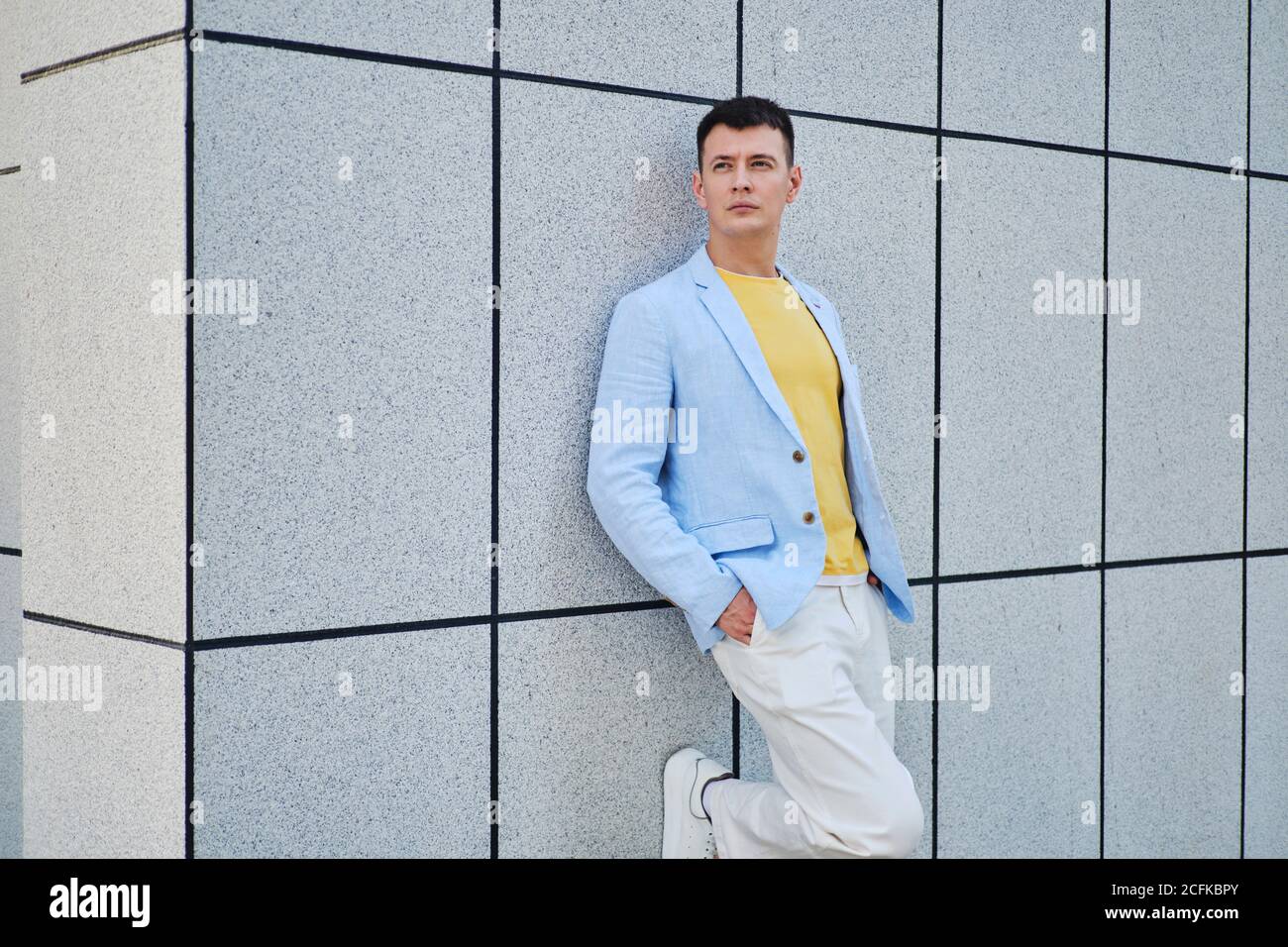 Young man on the street leaning on wall and looking away Stock Photo