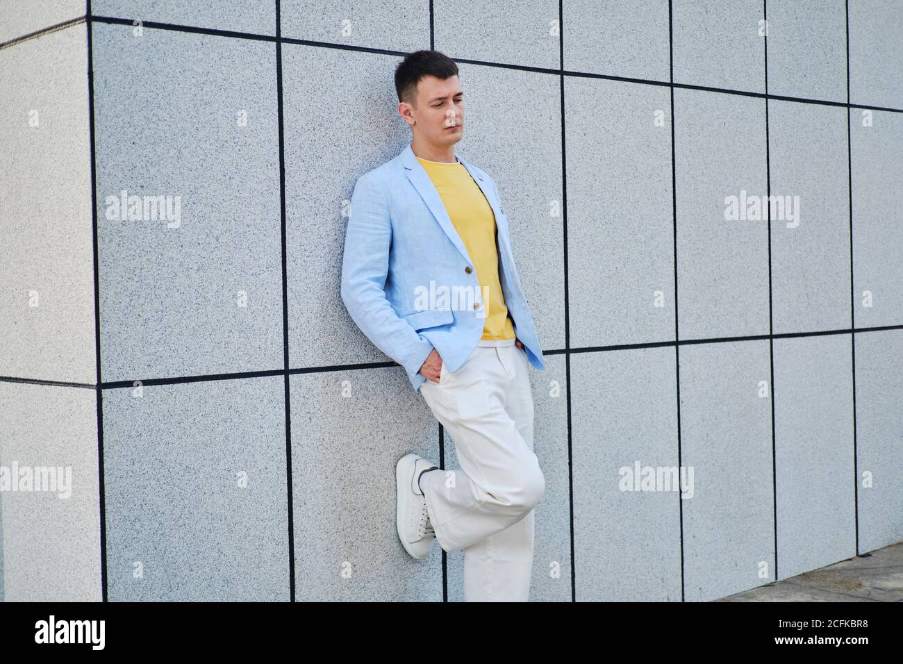 Young man on the street leaning on wall and looking down Stock Photo
