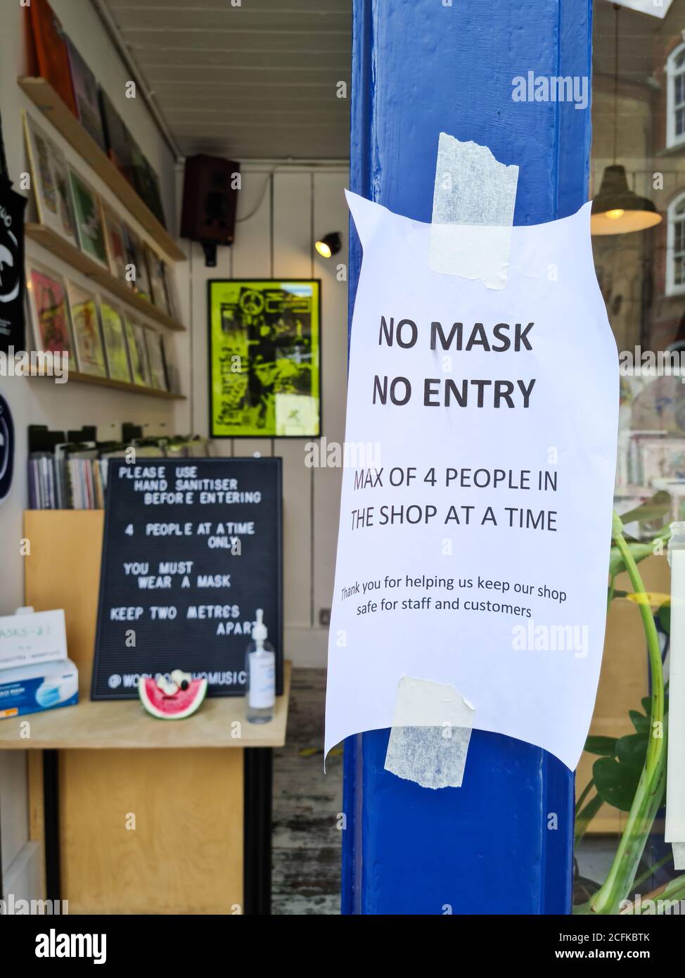 A sign by the entrance of a retail shop telling customers to wear face mask. Stock Photo