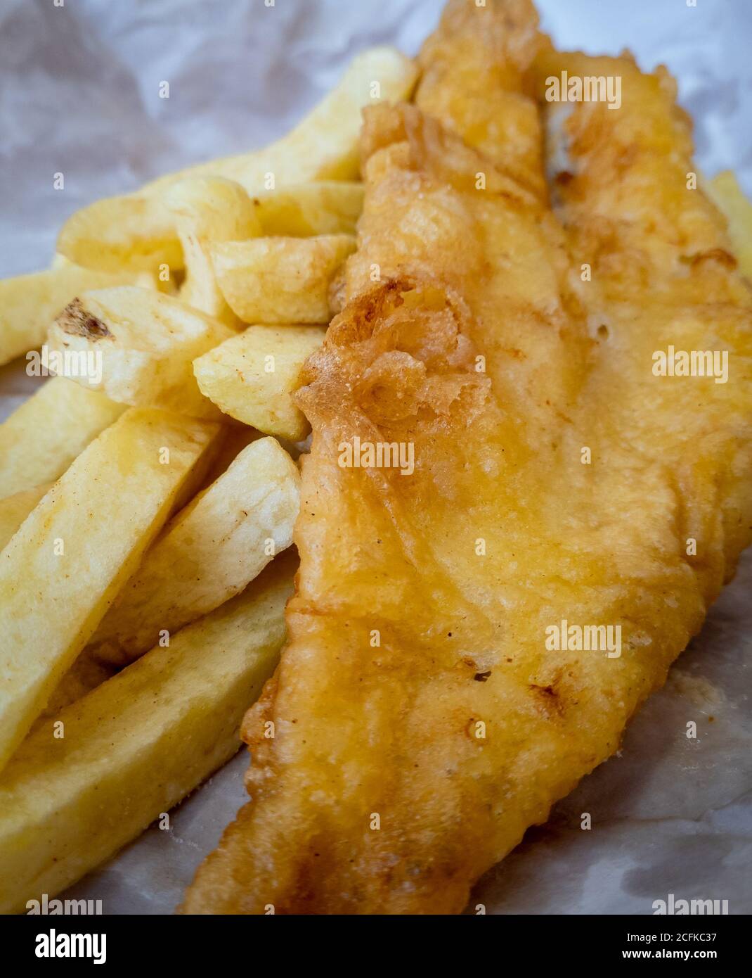 The British cultural cuisine Fish and Chips as served by the chips shop wrapped in paper. Stock Photo