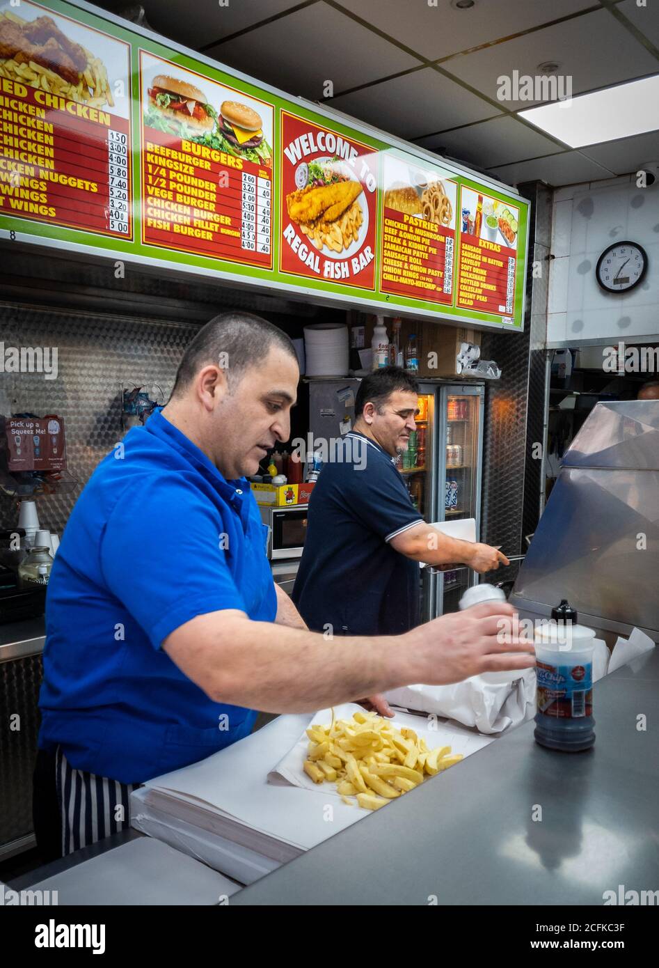 Fish and chips shop workers busy serving customers Stock Photo