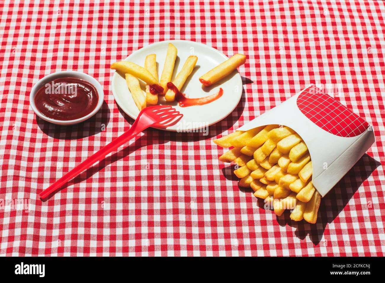 From above french fries packet near plate with potatoes soaked in