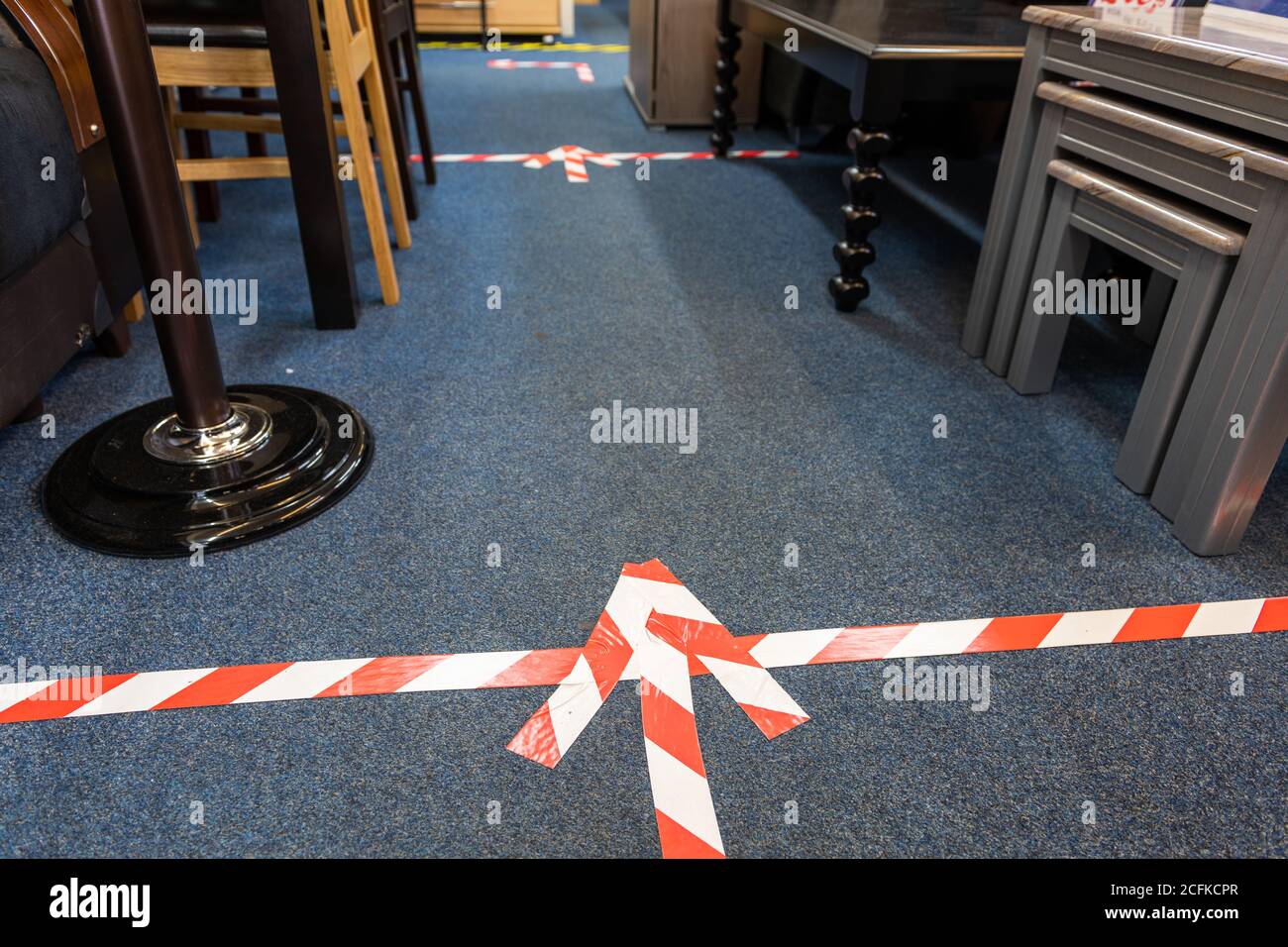 Social distancing floor markings in a small furniture retailer as required under government Covid-19 pandemic safety measures. Stock Photo