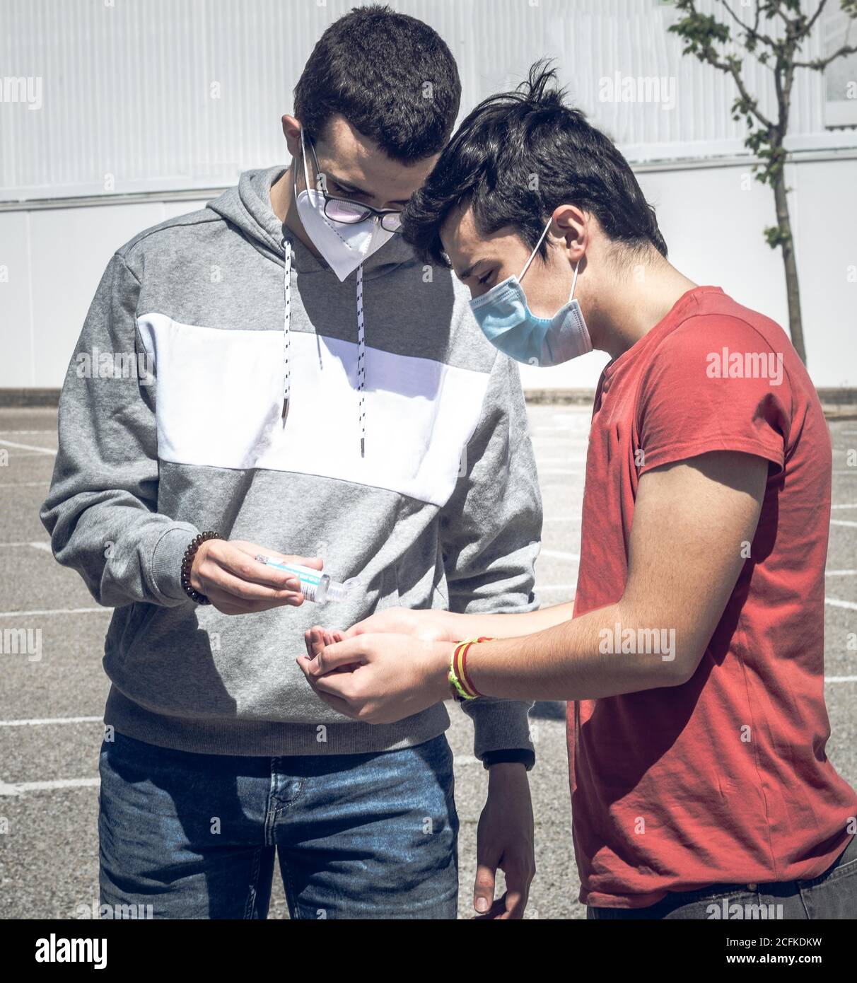 two young people sharing hydroalcoholic gel to disinfect themselves during the time of social distance to protect themselves from covid19 Stock Photo