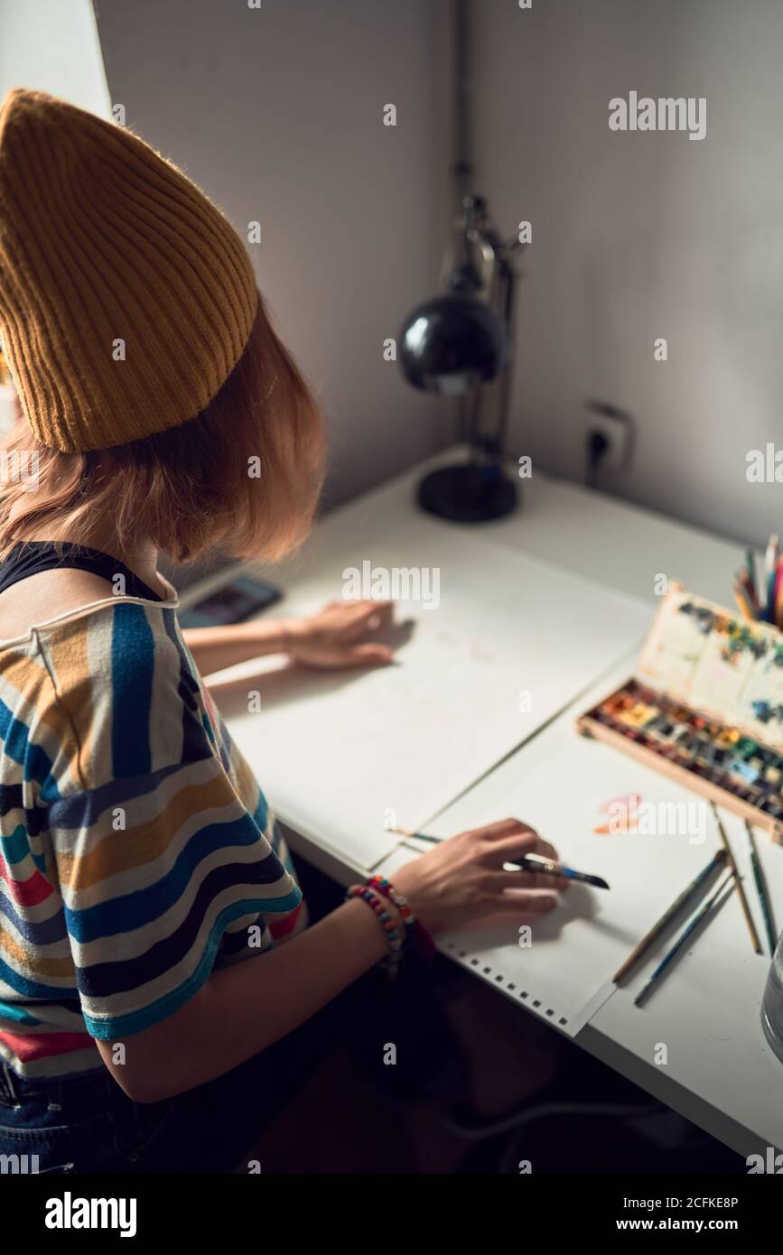 Side view of female artist standing at table with color wheel on paper