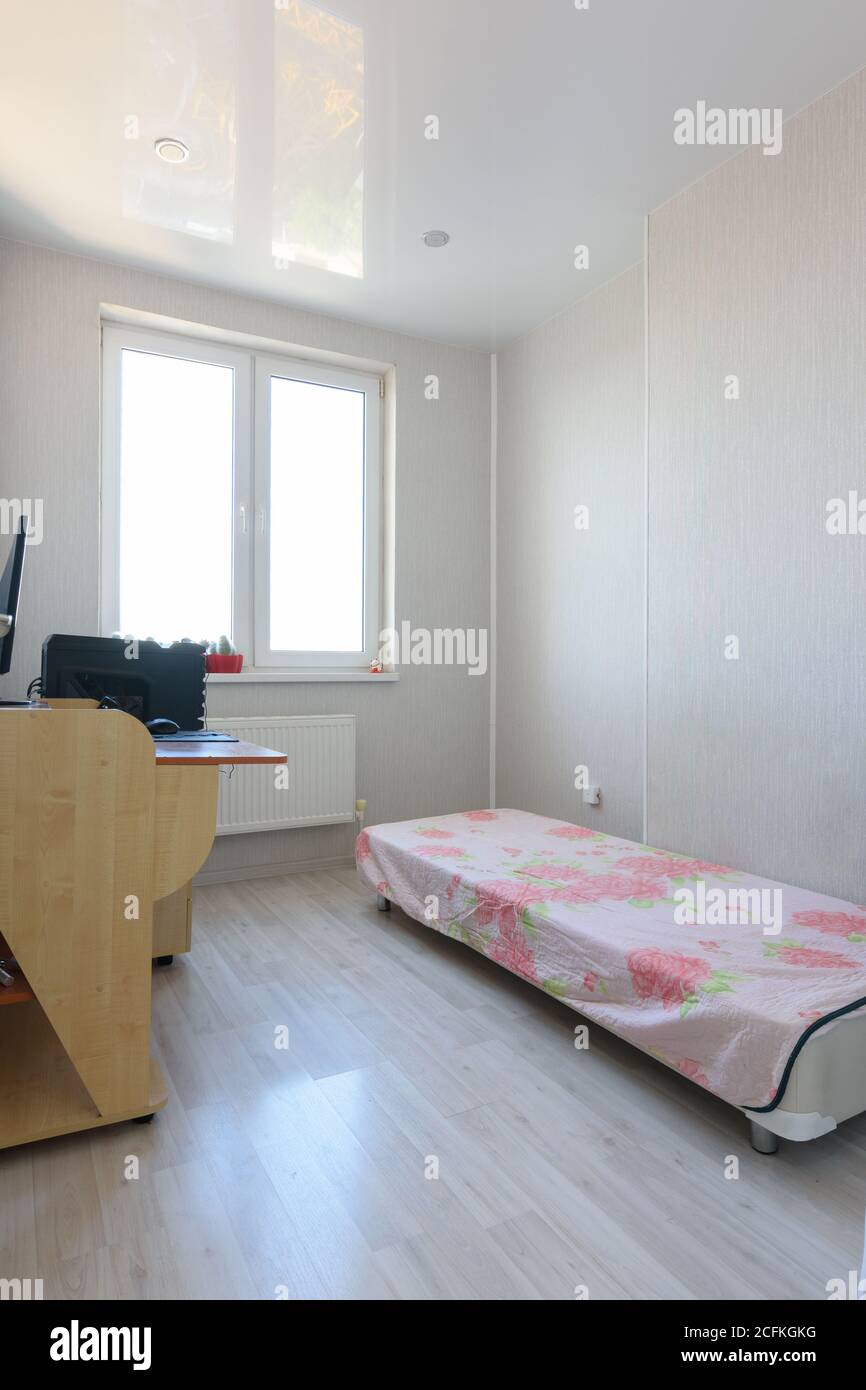Poor bedroom interior with sparse furniture and a computer table Stock