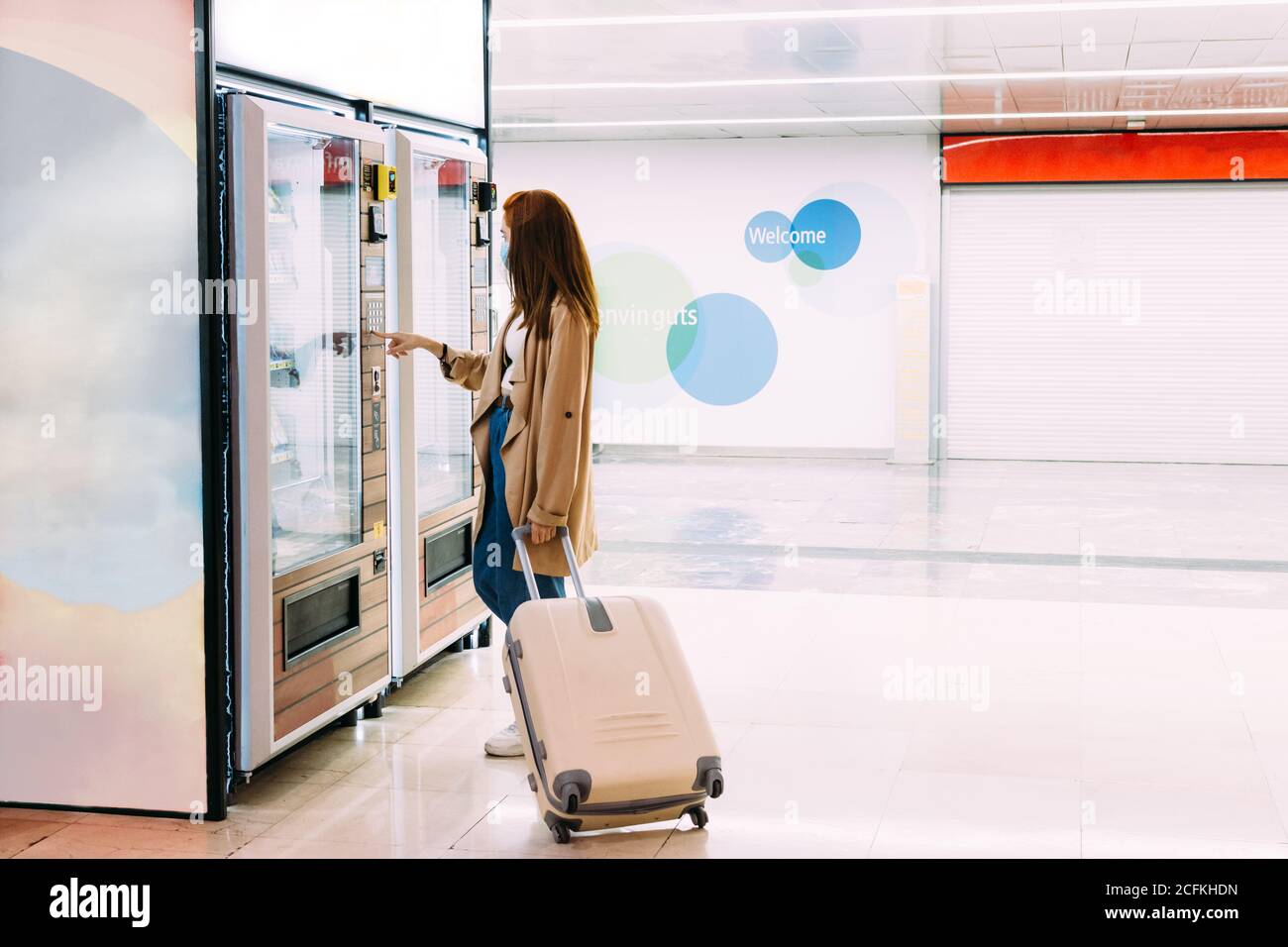 woman with a face mask uses the vending machine to buy a snack Stock Photo