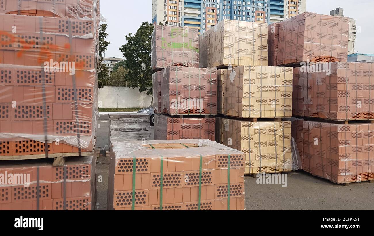 Red perforated bricks with rectangular holes on wooden pallets in an