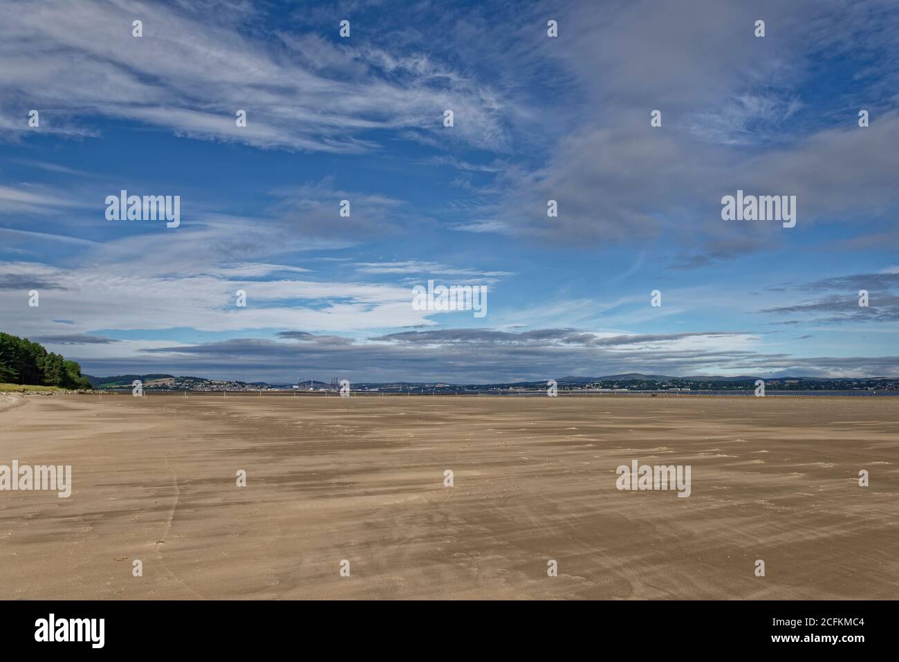 The Wide sandy gently shelving beach of the Tay estuary with Dundee and the Coast of Angus under the sunny light of an early morning in August. Stock Photo