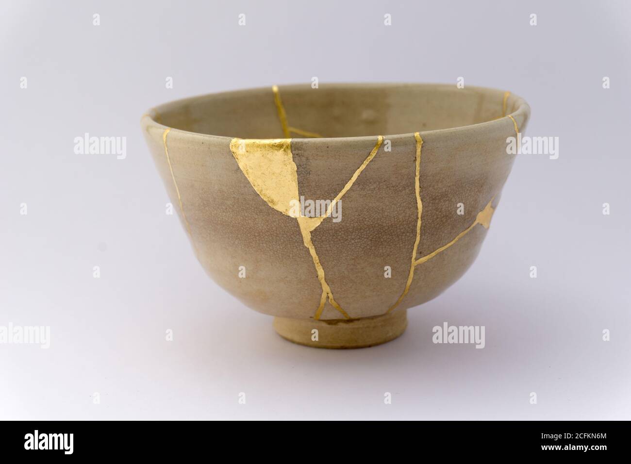 Kintsugi beige tea ceremony bowl. Gold cracks restoration on old