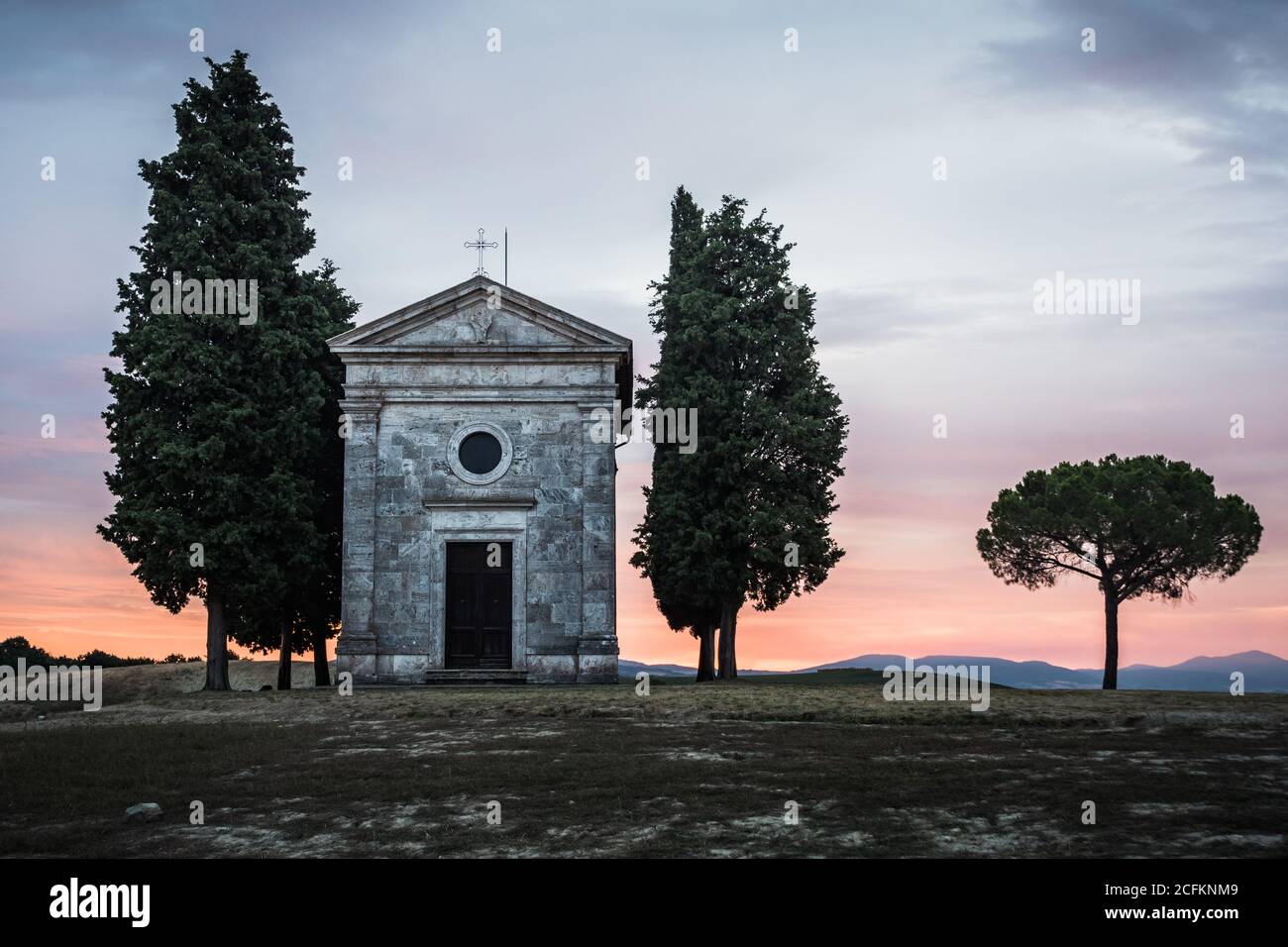 Chapel Cappella della Madonna di Vitaleta in Val d' Orcia, Tuscany, Italy at Sunrise or Dawn in the Romantic and Mysterious First Light Stock Photo