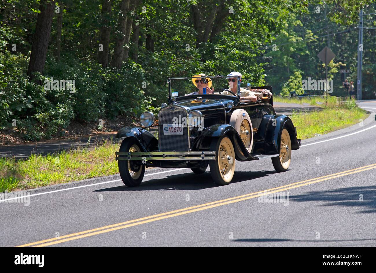 An antique Ford roadster heading down a Cape Cod road. Stock Photo