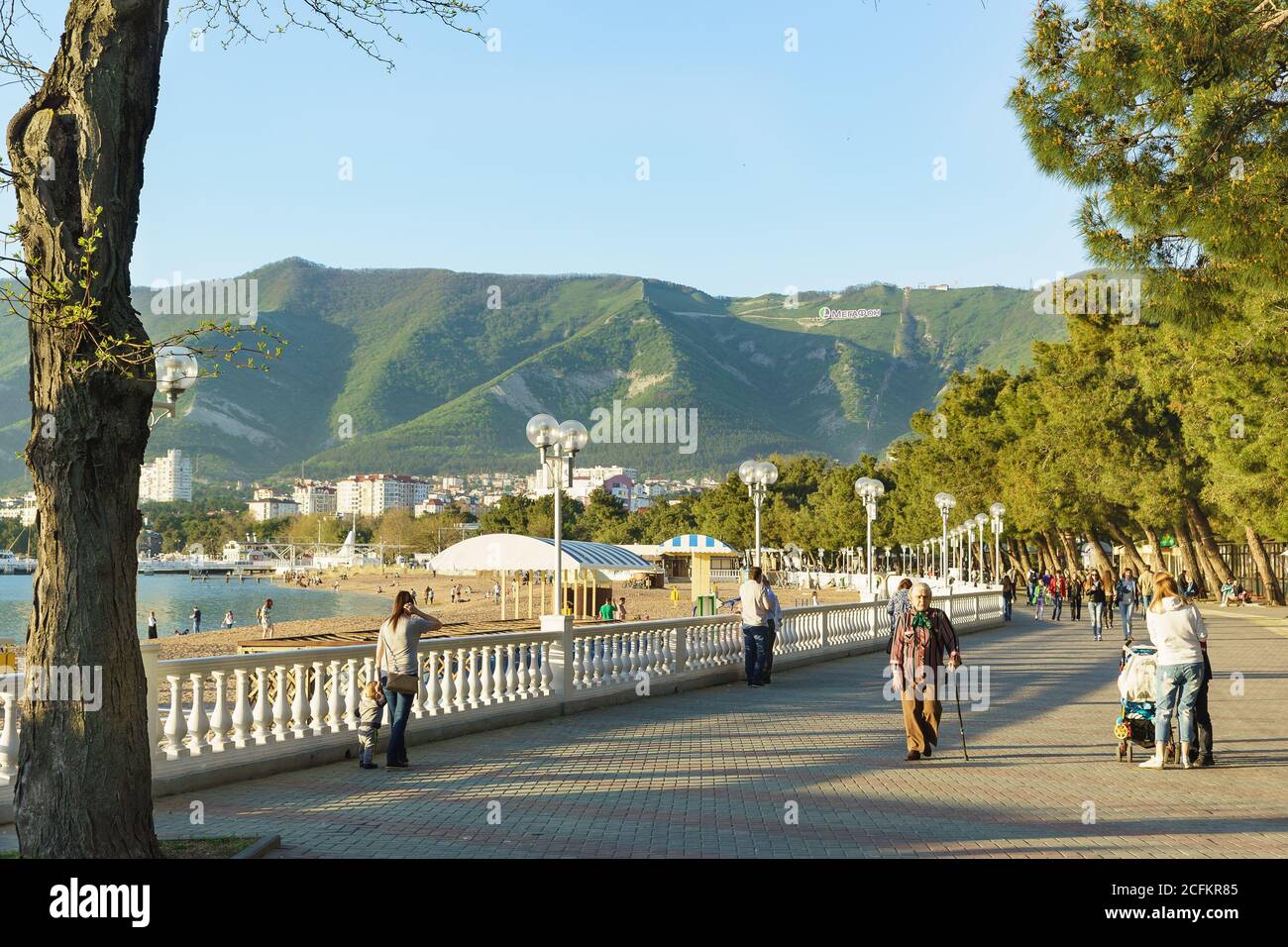 Gelendzhik, Krasnodar Krai, Russia - April 29.2017: People walk along the embankment of Gelendzhik on the background of mountains in the rays of the s Stock Photo